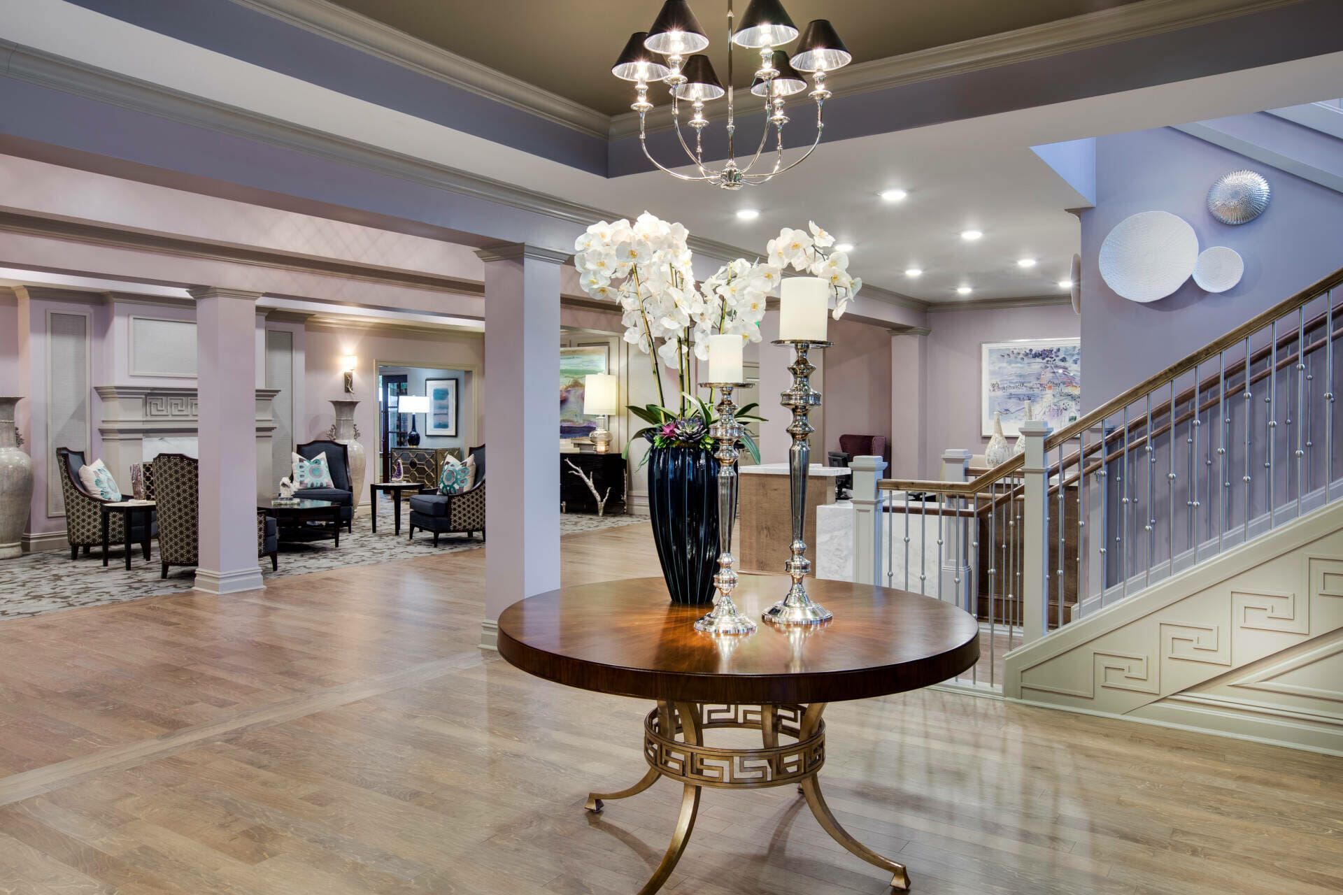 A hotel lobby with a round table and a vase of flowers on it.