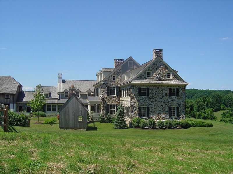 A large stone house sits in the middle of a grassy field