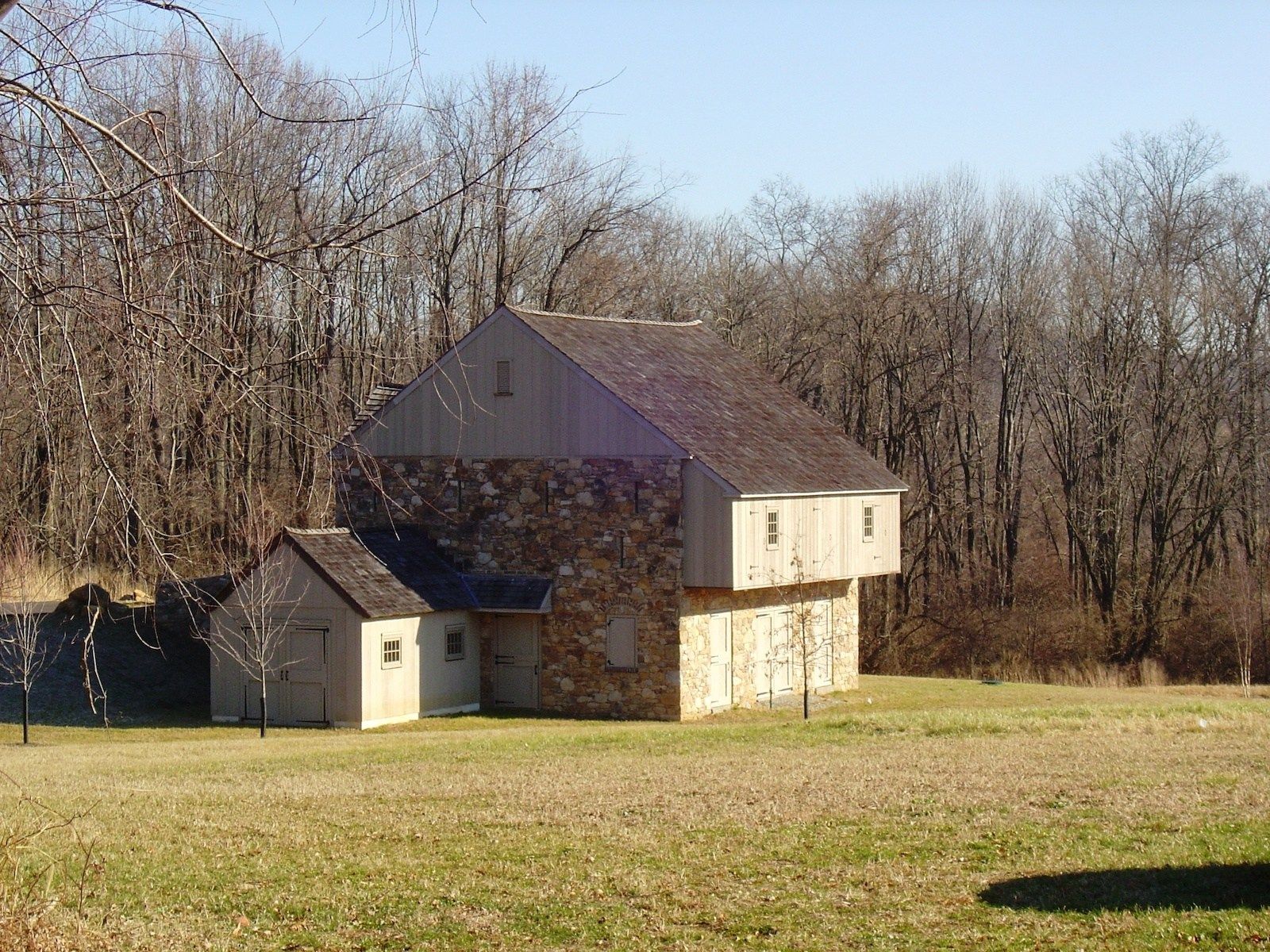 A house in the middle of a field with trees in the background