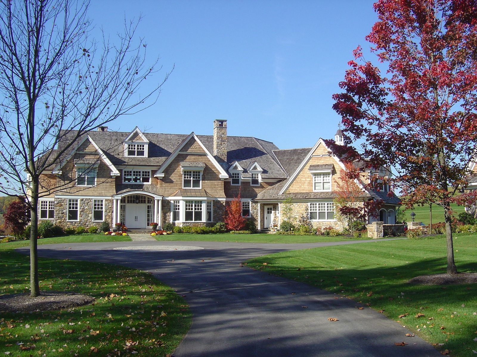 A large house with a driveway and trees in front of it