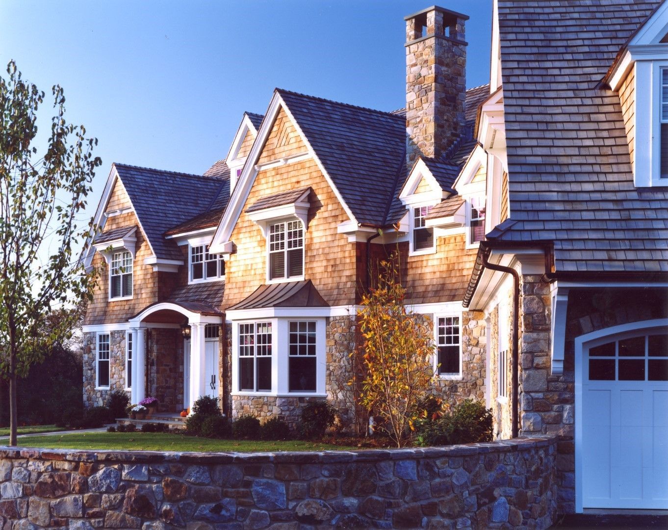 A large house with a stone wall and a white garage door