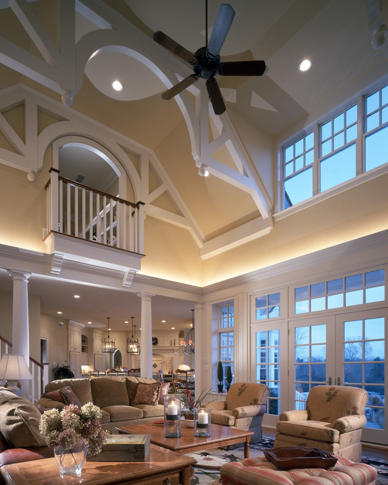 A living room with a ceiling fan and lots of windows