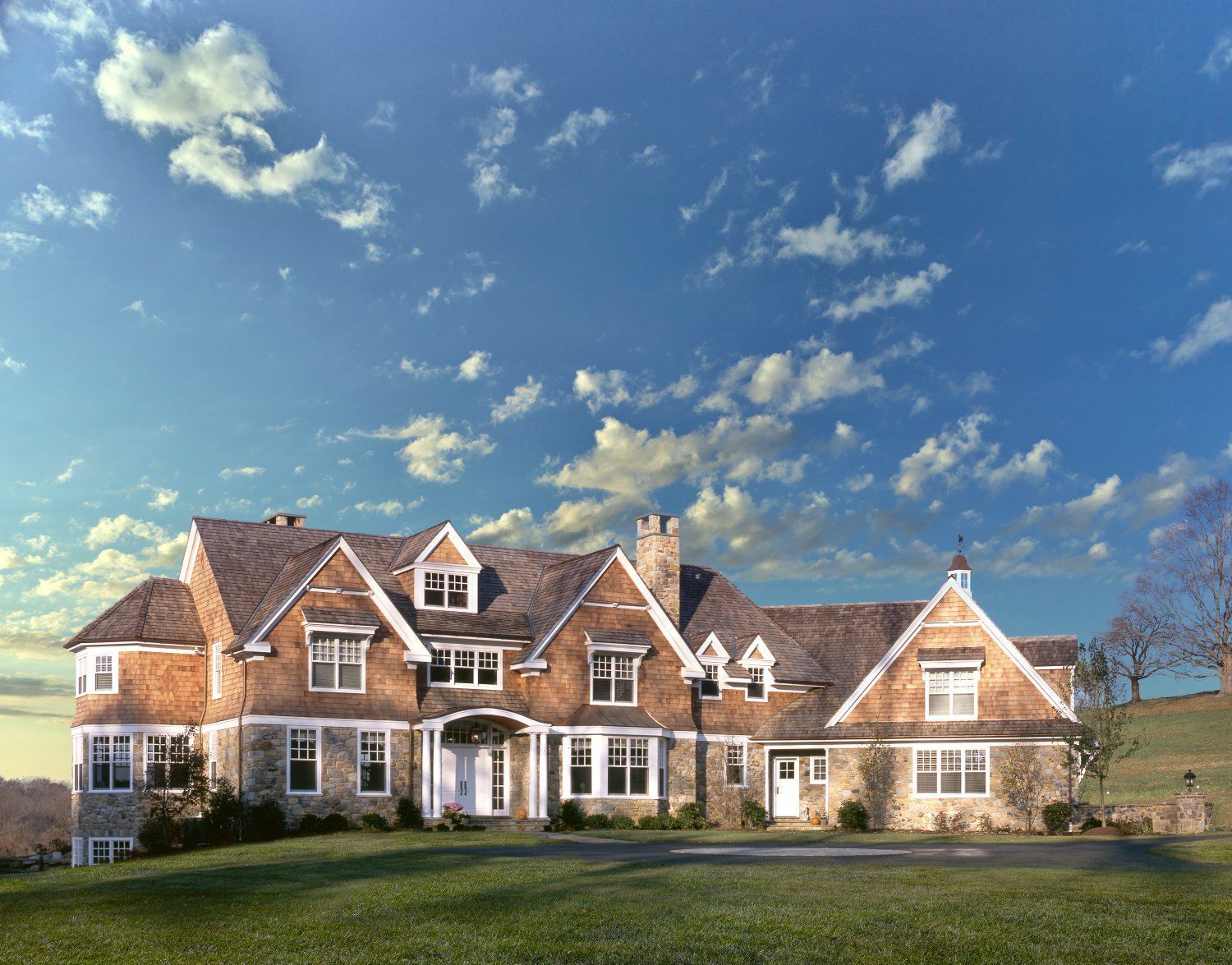 A large house with a blue sky and clouds behind it