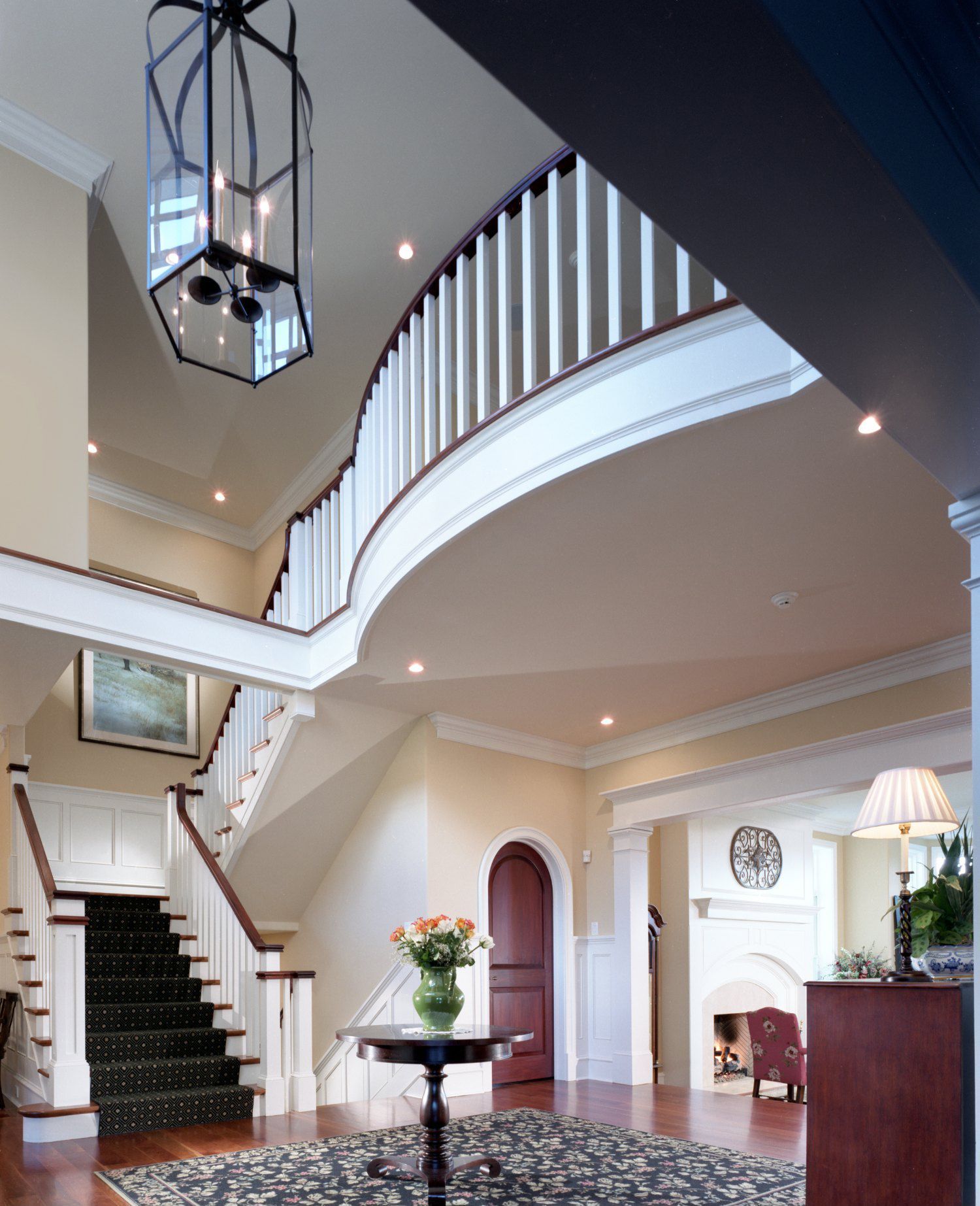 A room with a staircase and a table with flowers on it
