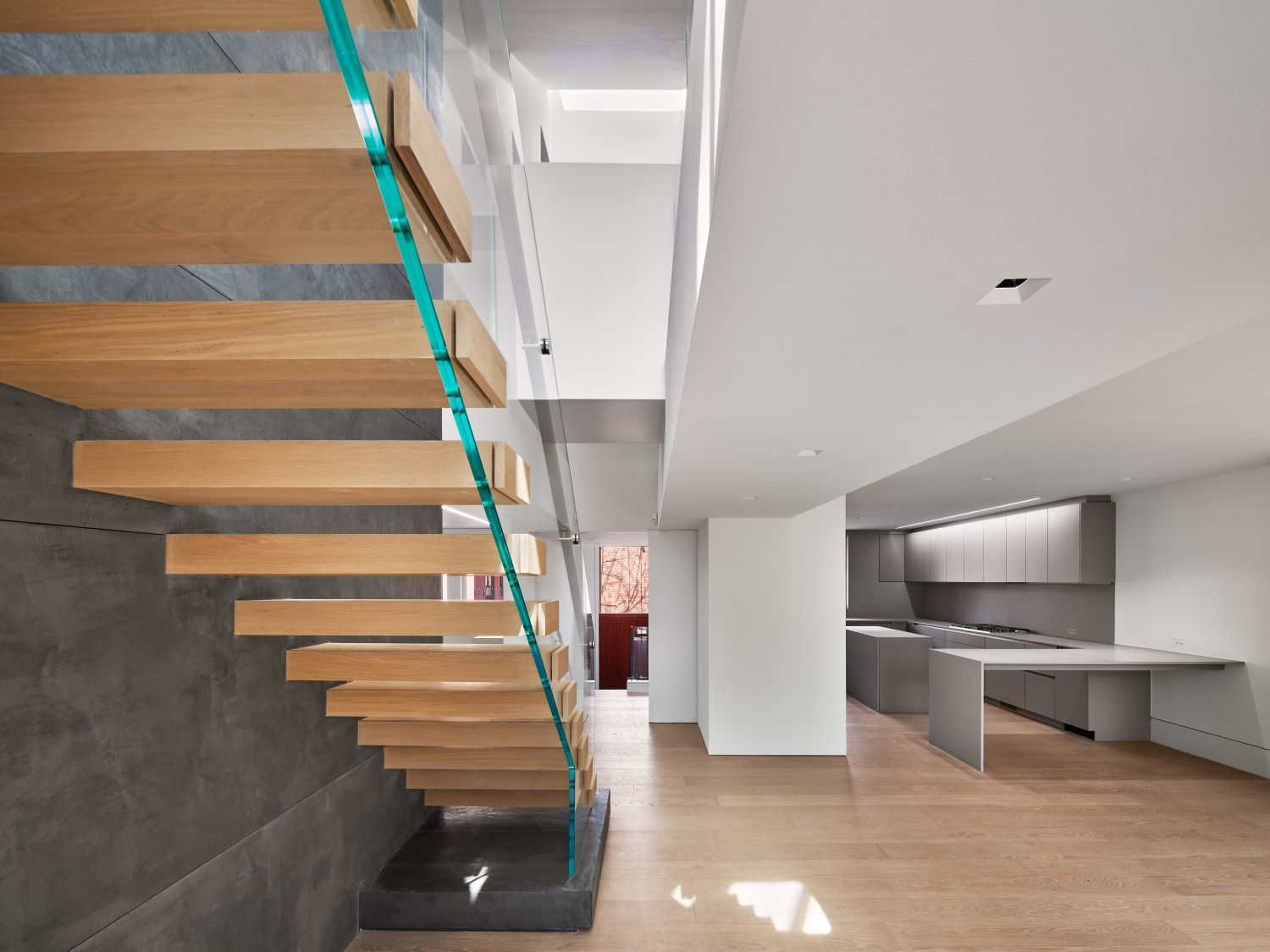 A wooden staircase with a glass railing in a house