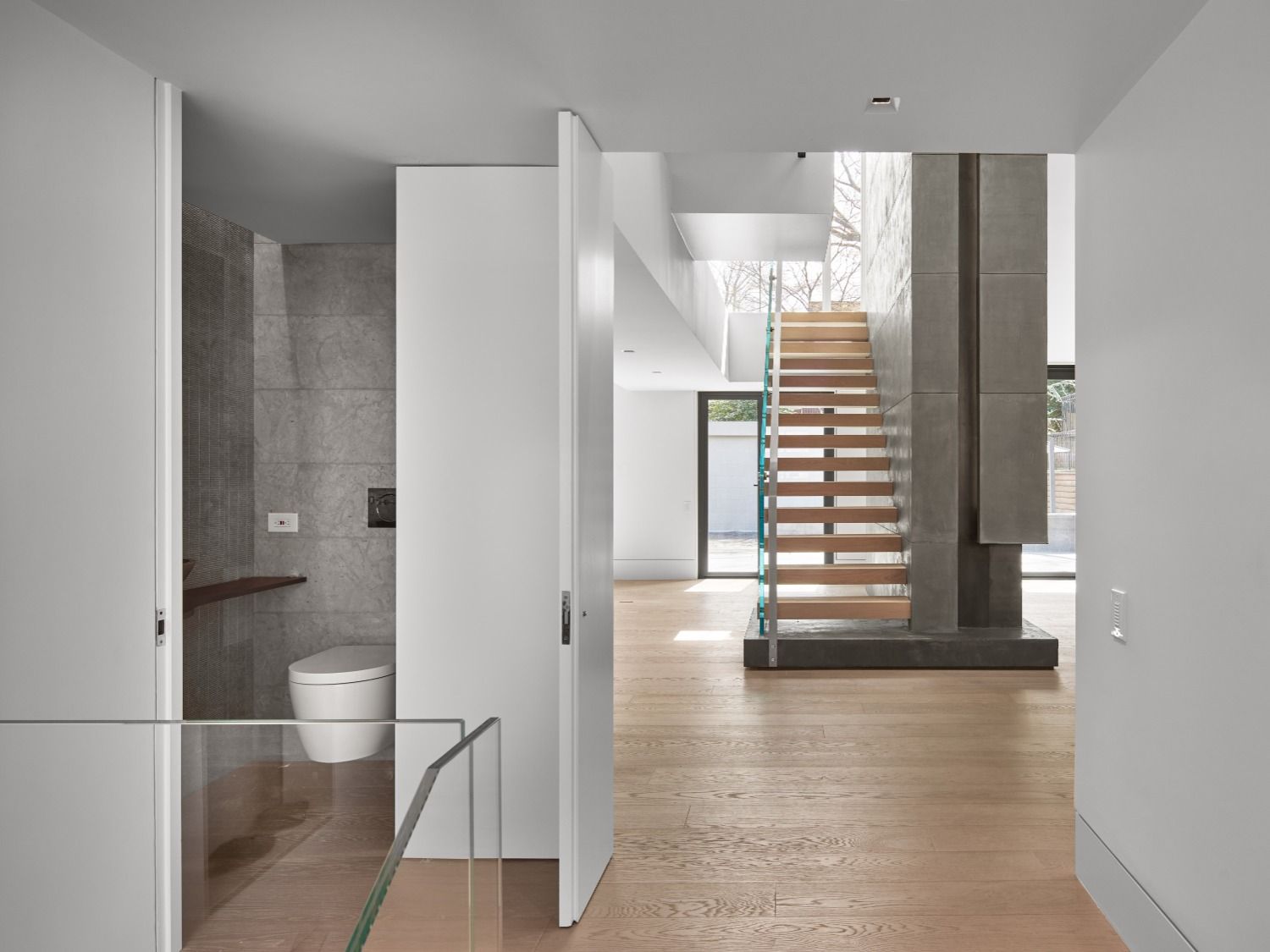 A hallway with a toilet and stairs in a house