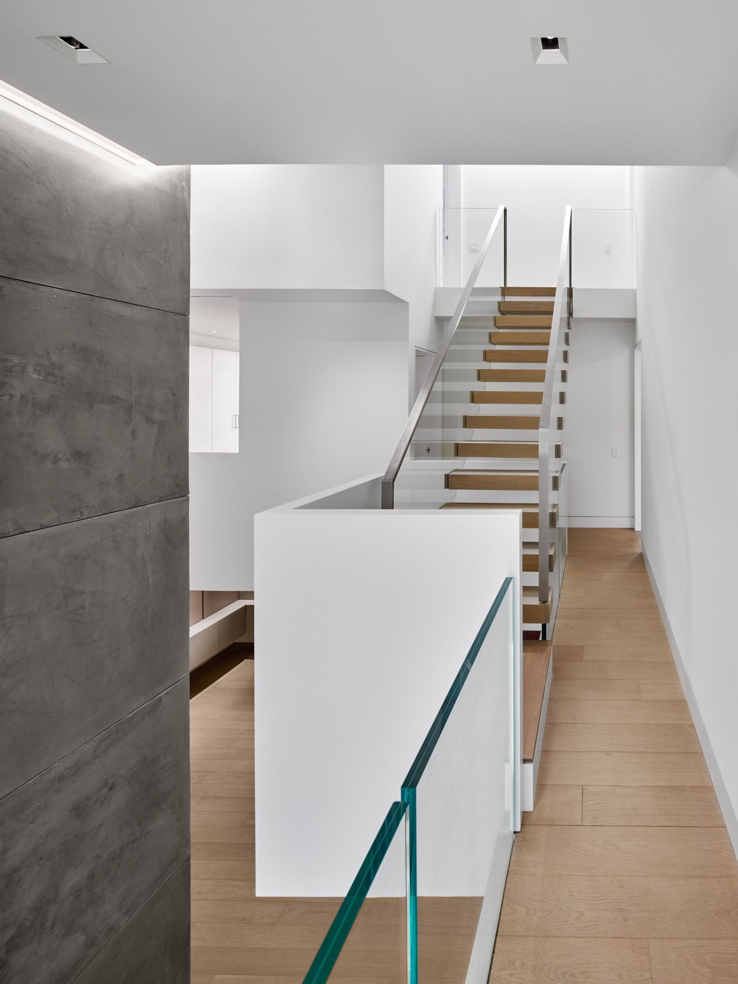 A hallway with a staircase and a glass railing