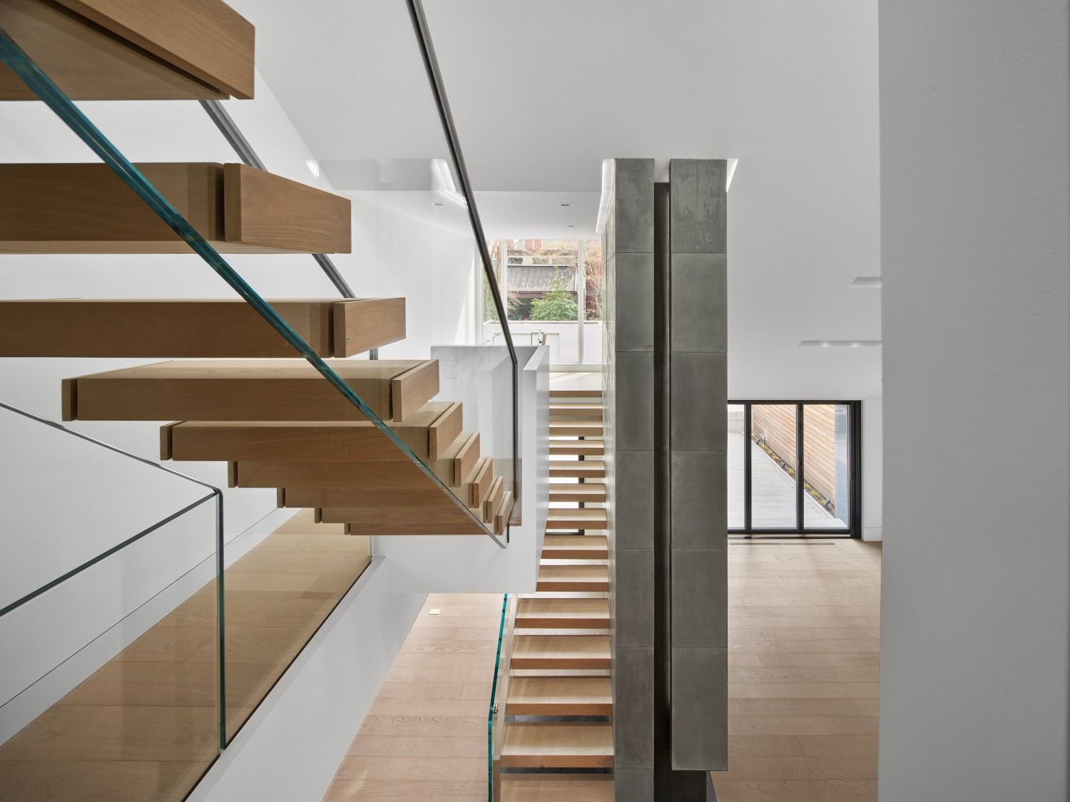 A wooden staircase with a glass railing in a house.