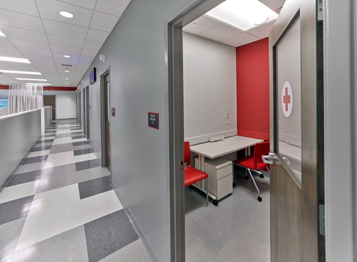 A hallway in a hospital with a red cross on the wall