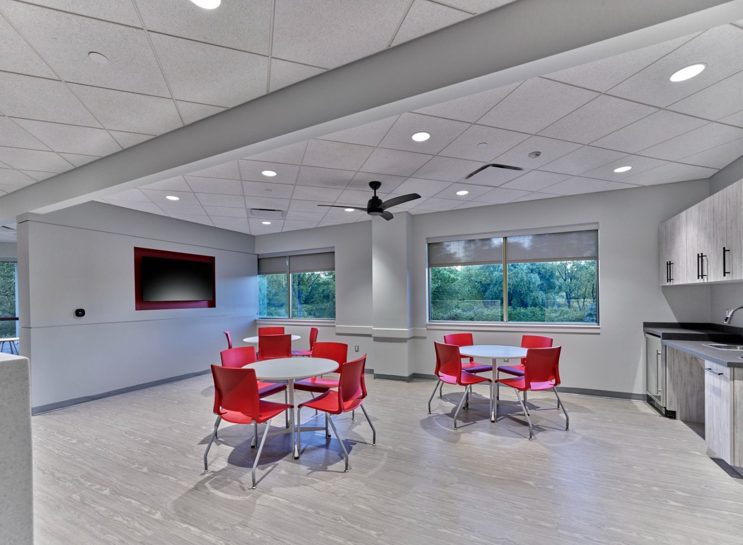 A large room with tables and chairs and a ceiling fan.
