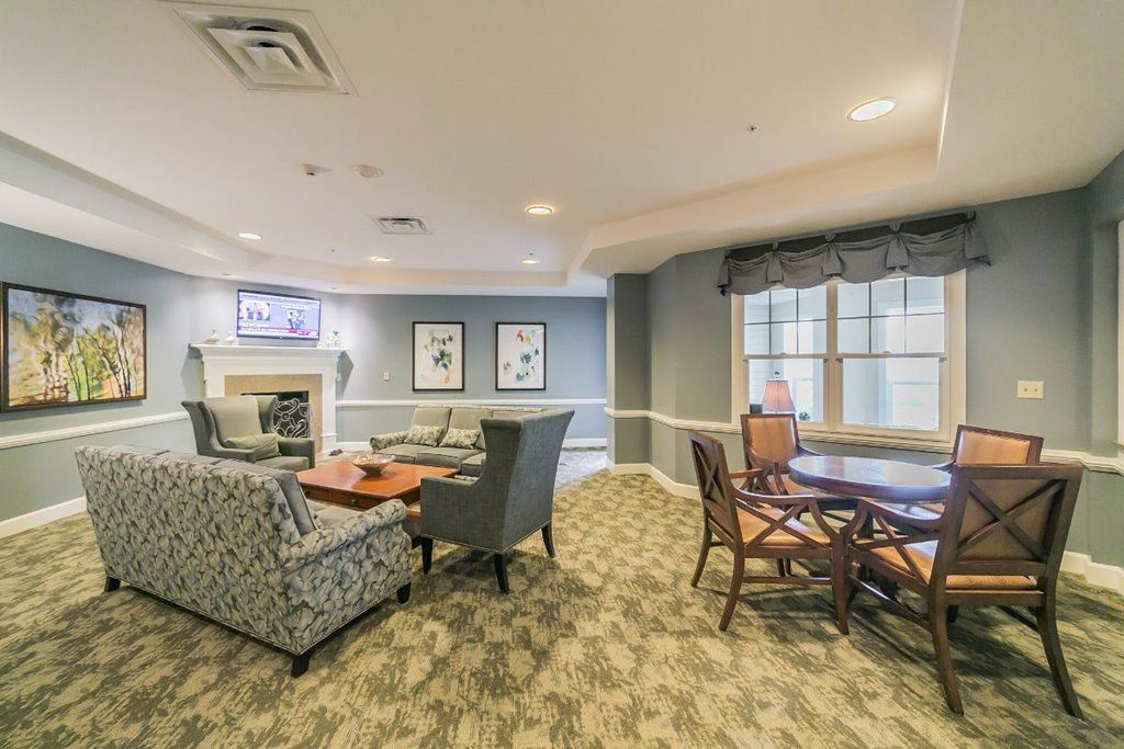 A living room with a couch , chairs , a table and a fireplace.