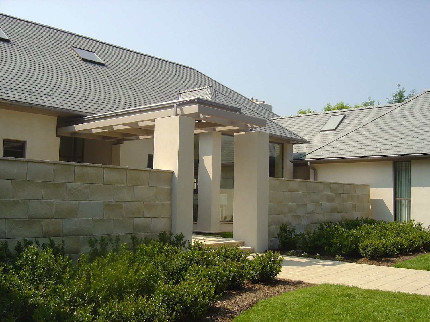 A house with a gray roof and a stone wall