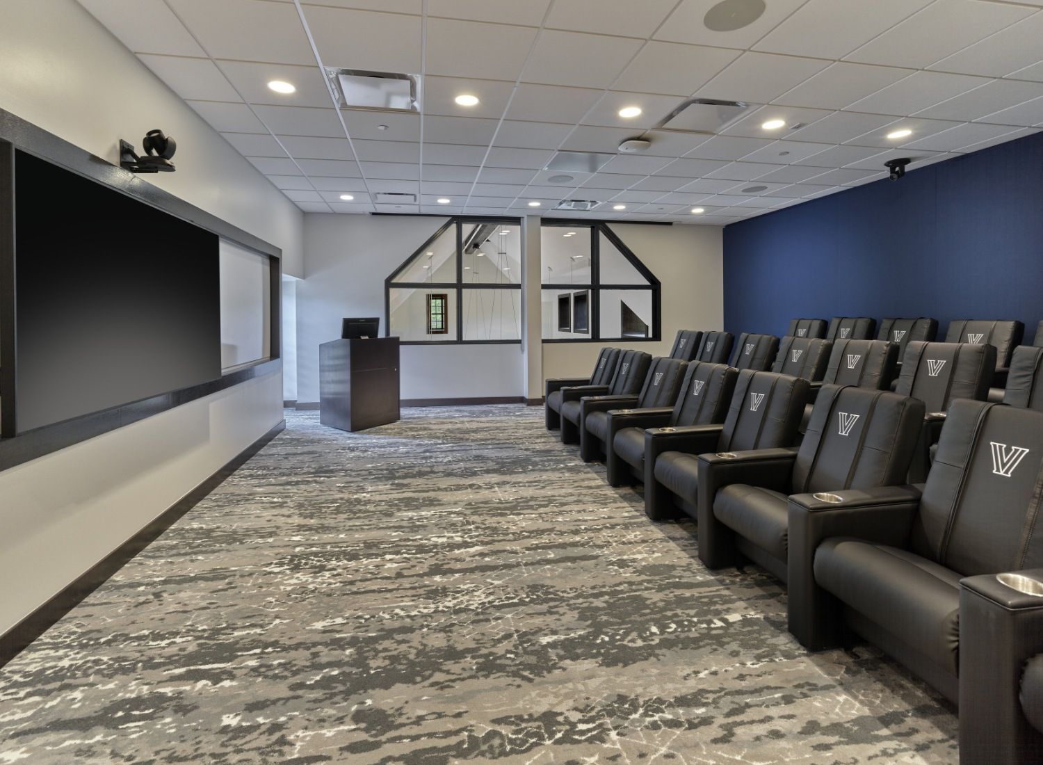 A large room with a lot of chairs and a large screen.