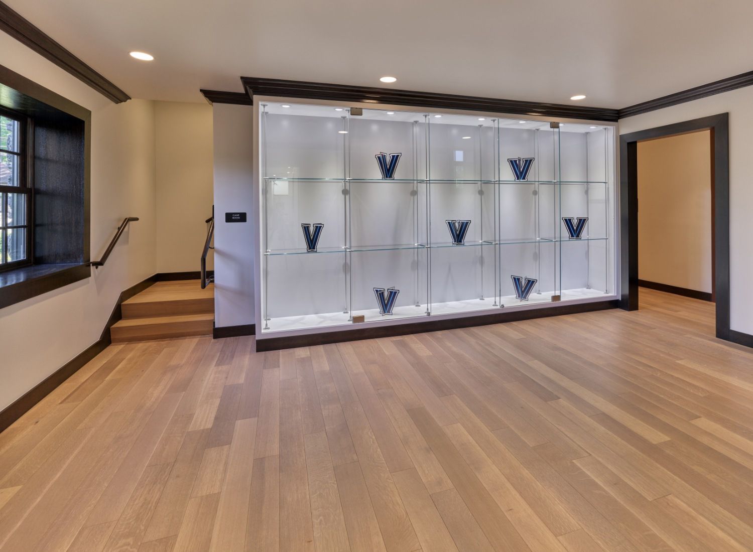 An empty room with hardwood floors and a glass display case.
