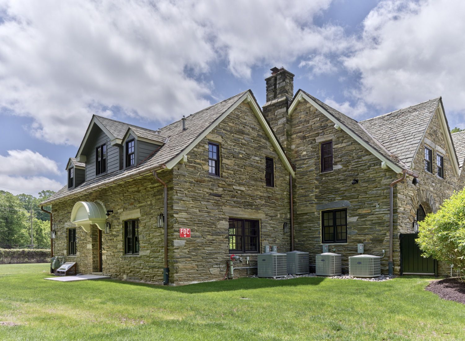 A large stone house with a large lawn in front of it.