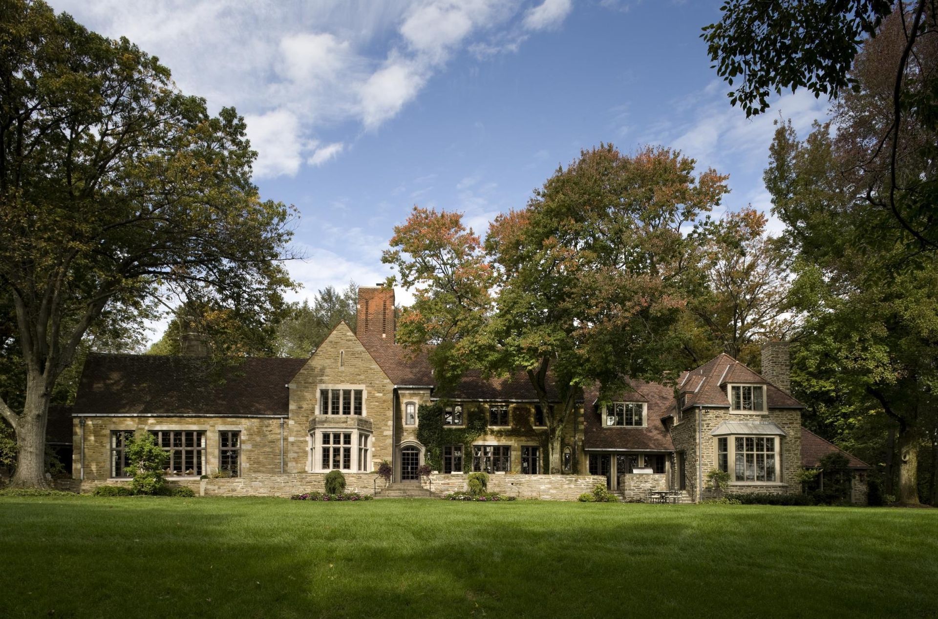 A large house sits in the middle of a lush green field