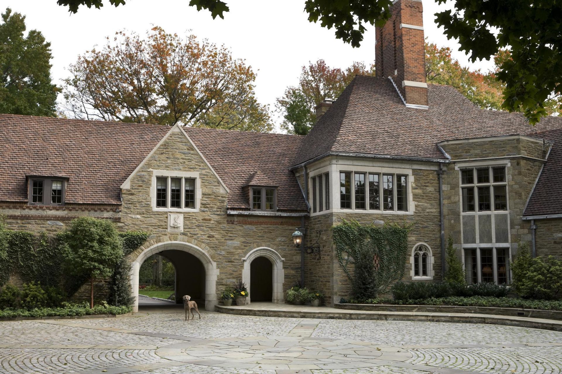 A large stone house with a cobblestone driveway leading to it