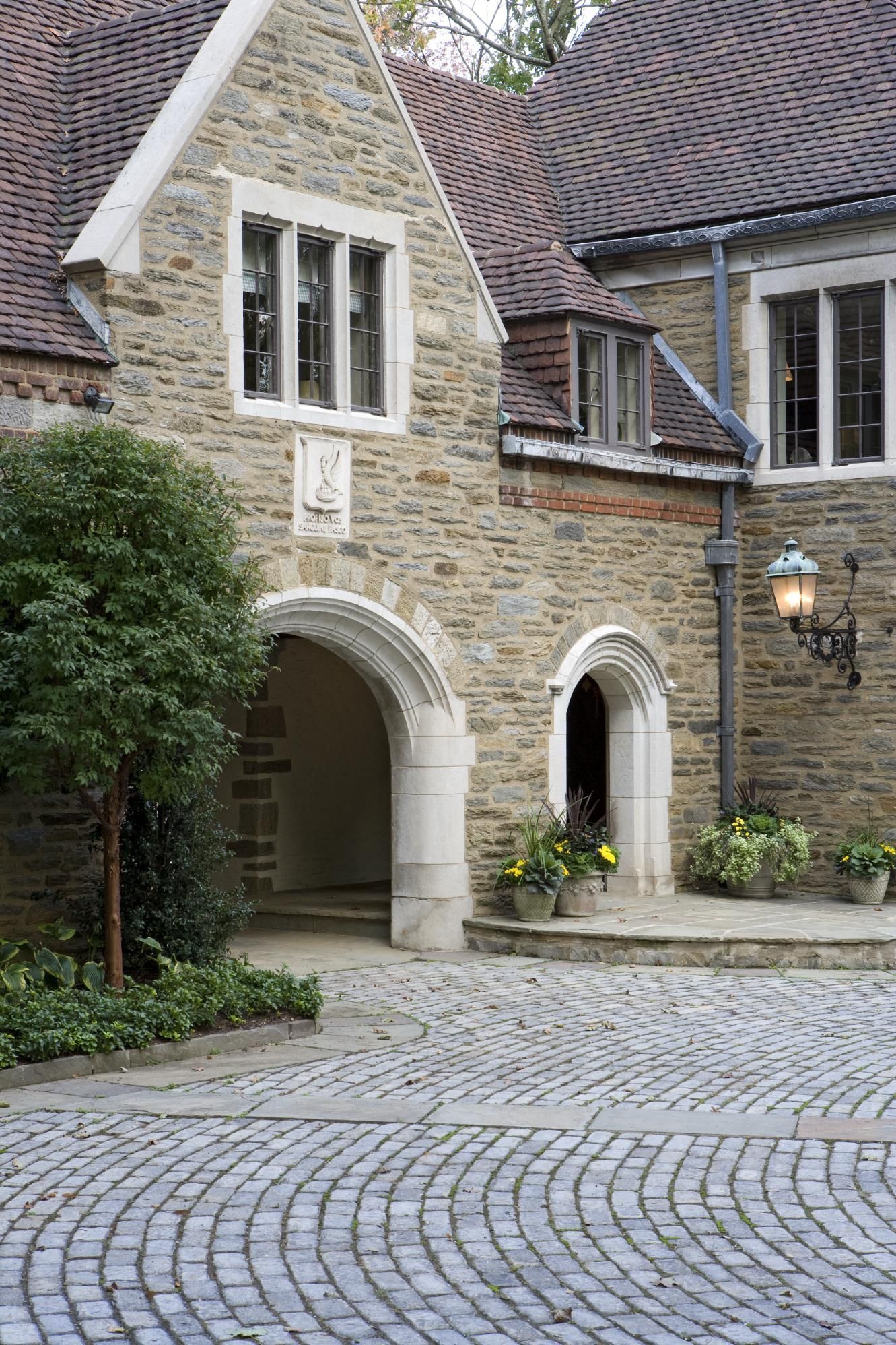 A large stone building with a cobblestone driveway in front of it.