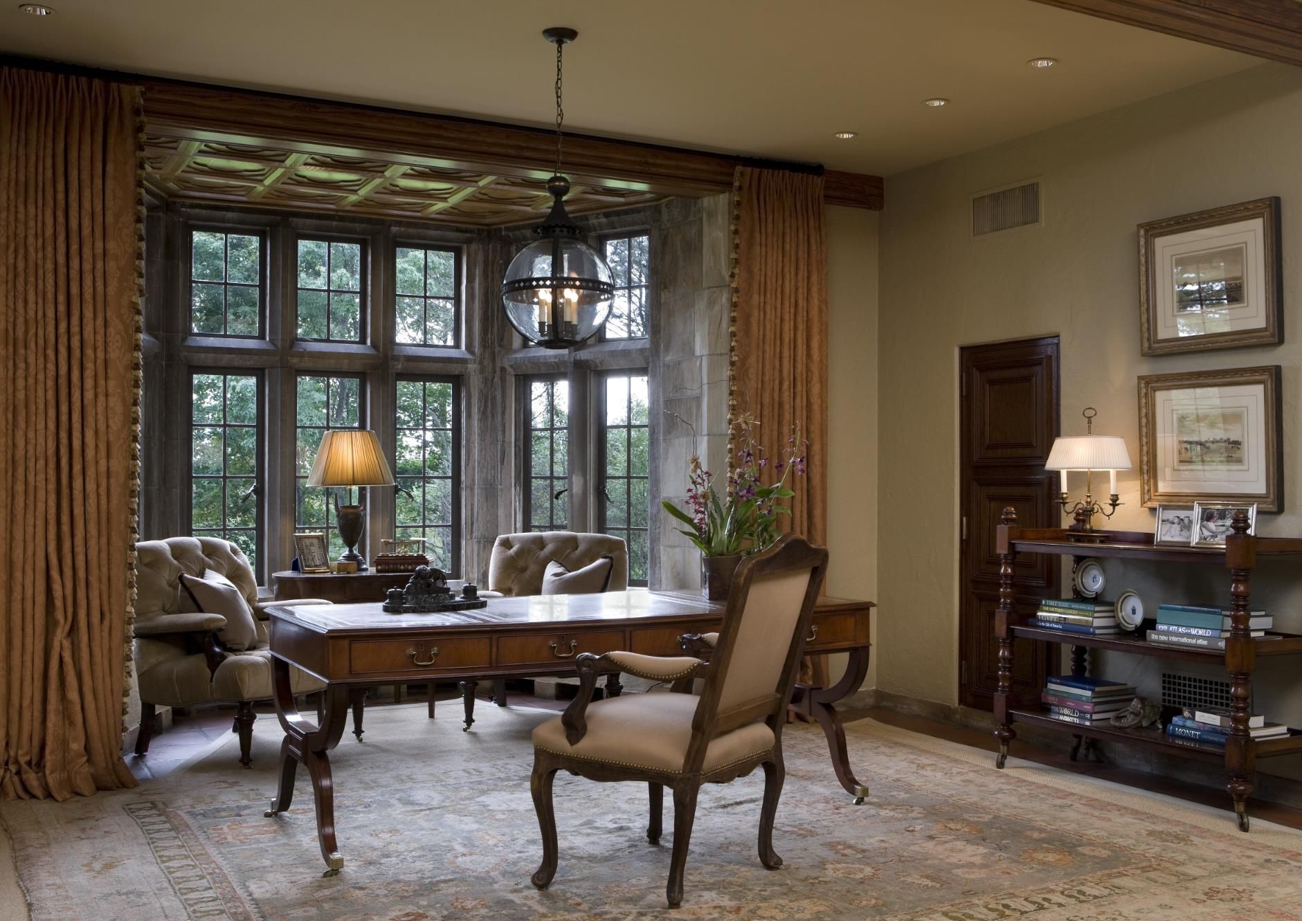 A living room with a desk and chairs and a large window