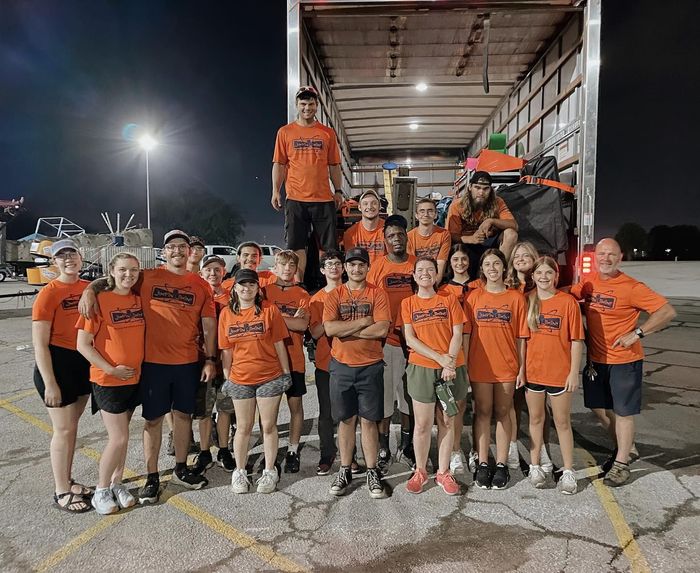 A group of people are posing for a picture in front of a truck.