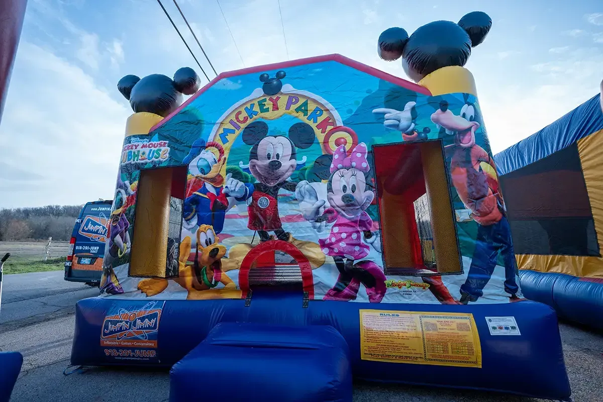 A mickey mouse bouncy house is sitting on the side of the road.