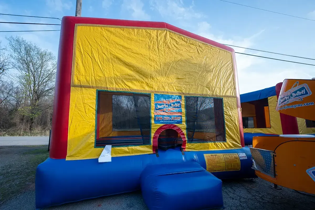 A red , yellow and blue bouncy house is sitting on the side of the road.
