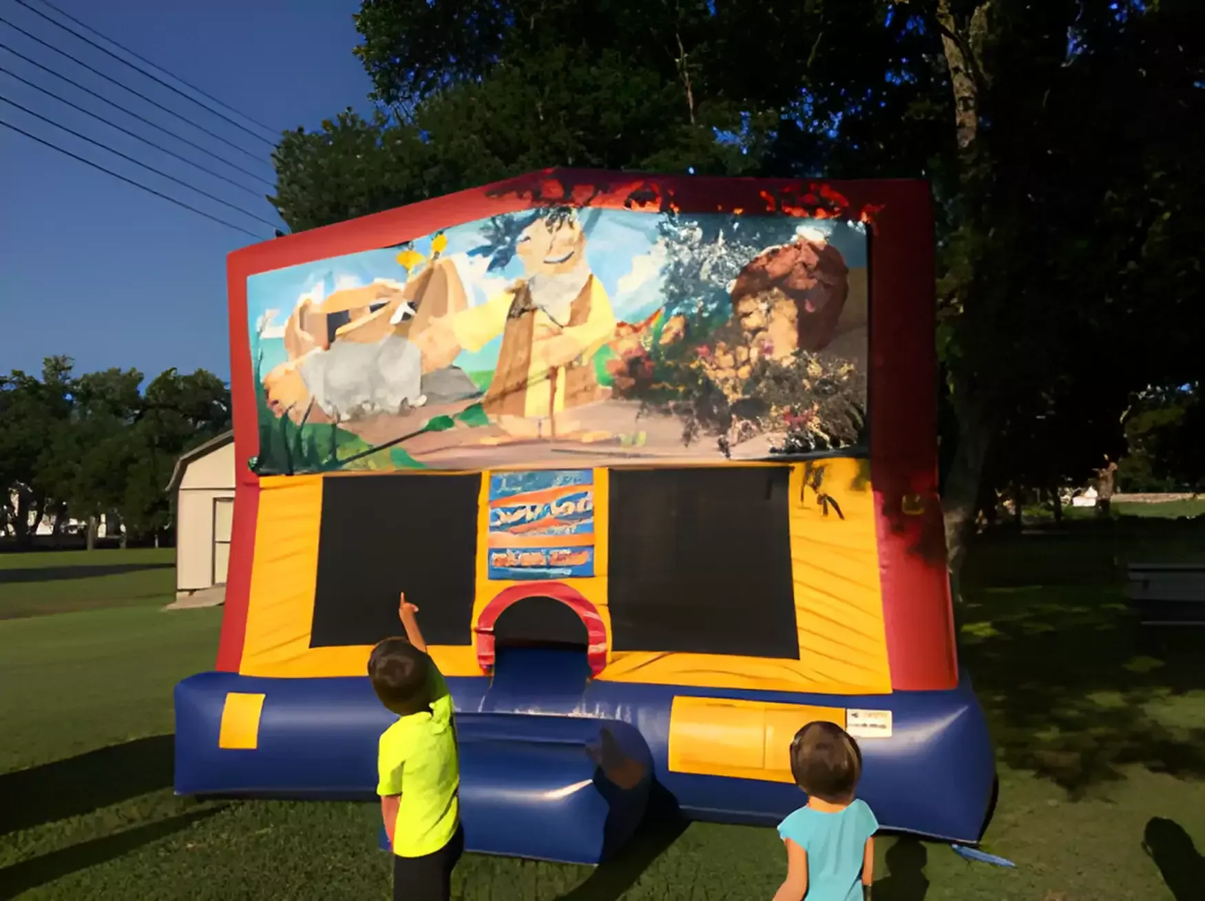 Two children are standing in front of a bouncy house.