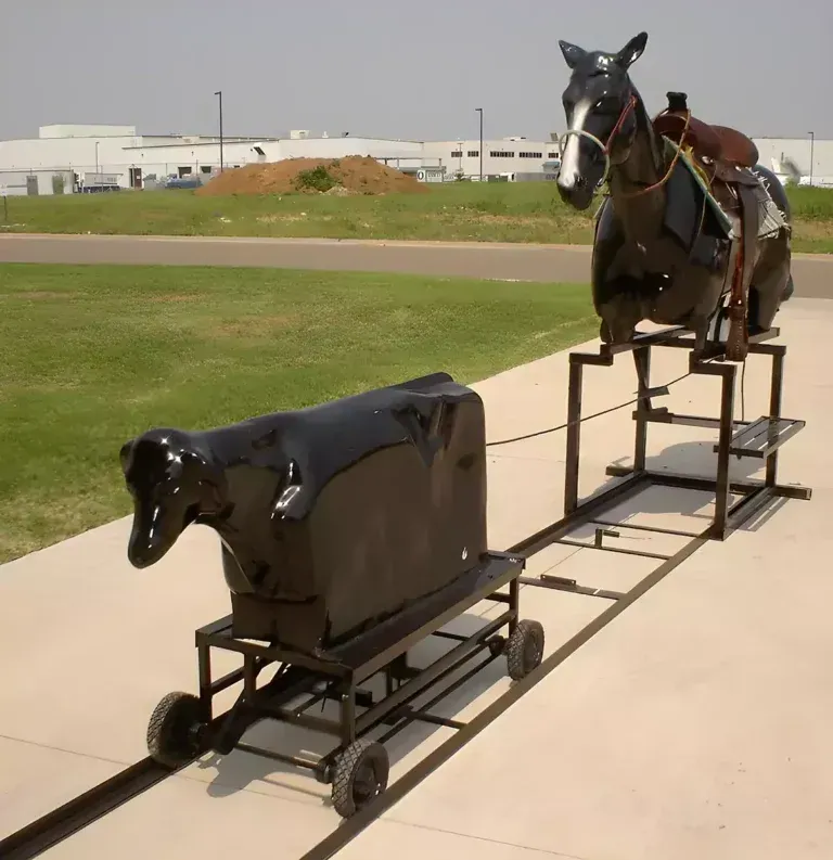 A statue of a horse pulling a cow on a cart