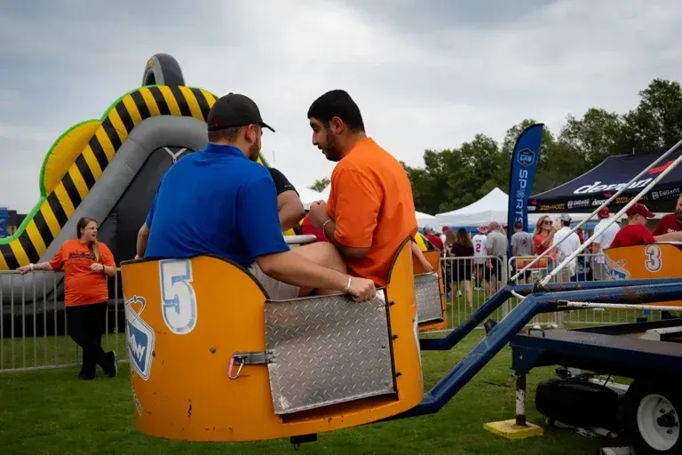 Two men are riding a carnival ride with the number 5 on it.
