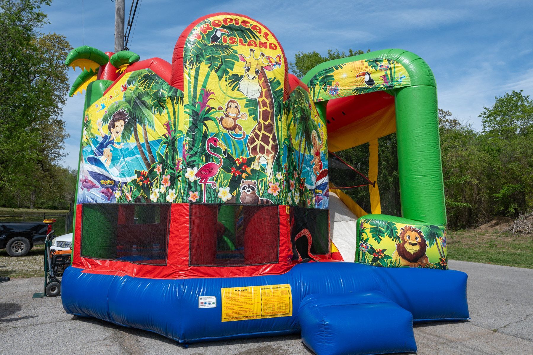 Colorful inflatable jungle-themed bounce house with a slide and depictions of animals.