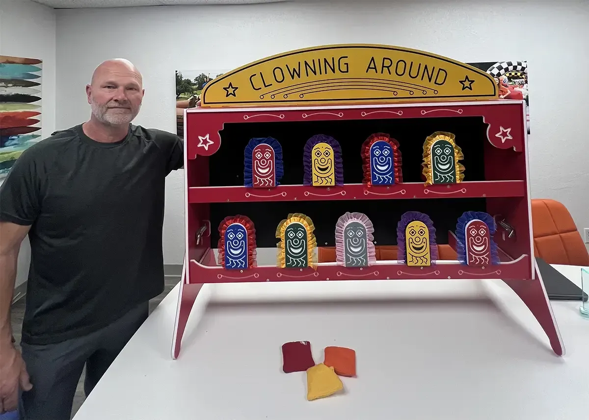 A man is standing next to a clowning around game.
