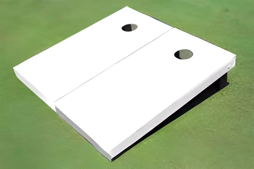A white cornhole board is sitting on top of a green field.