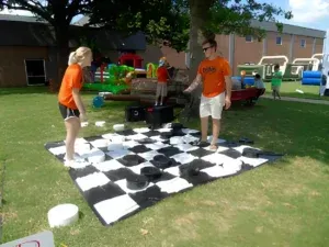 A man and a woman are playing a game of checkers on a giant checkerboard.