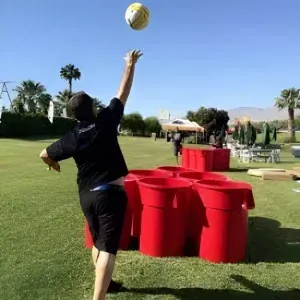 A man is throwing a volleyball into the air in a field.