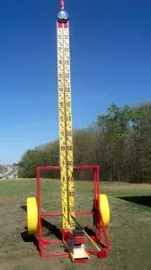 A giant hammer is sitting on top of a trailer in a field.