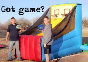 Two men are standing in front of an inflatable basketball hoop.