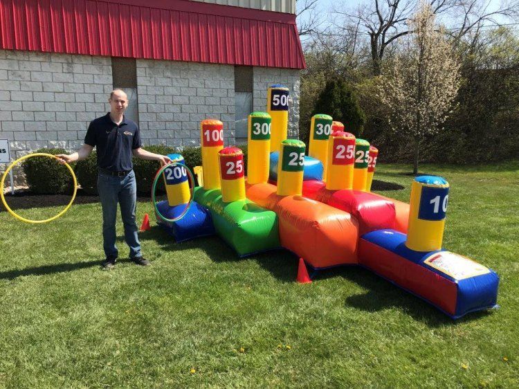 A man is standing in front of a colorful inflatable game.