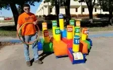 A man is holding a hula hoop in front of an inflatable ring toss game.