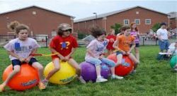 A group of children are sitting on bouncy balls in a field.
