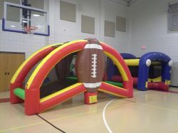 A large inflatable football is sitting on top of a basketball court.