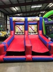 A red and blue bouncy house is sitting in a warehouse.