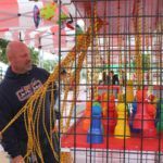 A man is standing in front of a fence holding a rope.