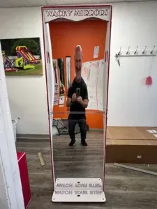 A man is taking a picture of himself in a wacky mirror.