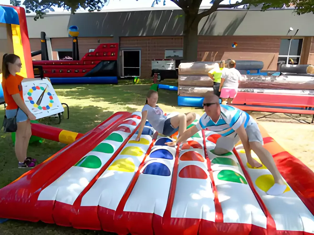 A group of children are standing in front of an inflatable water slide.