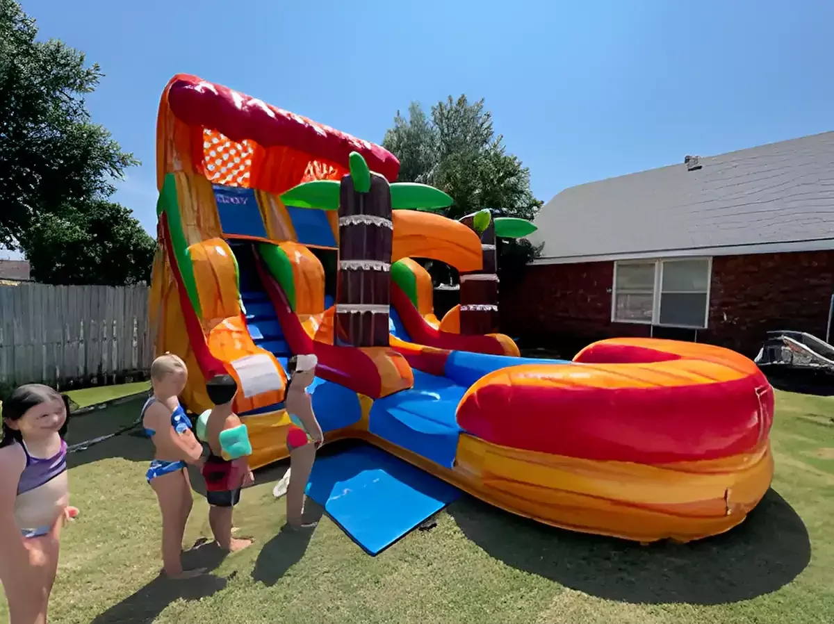 A group of children are standing in front of an inflatable water slide.