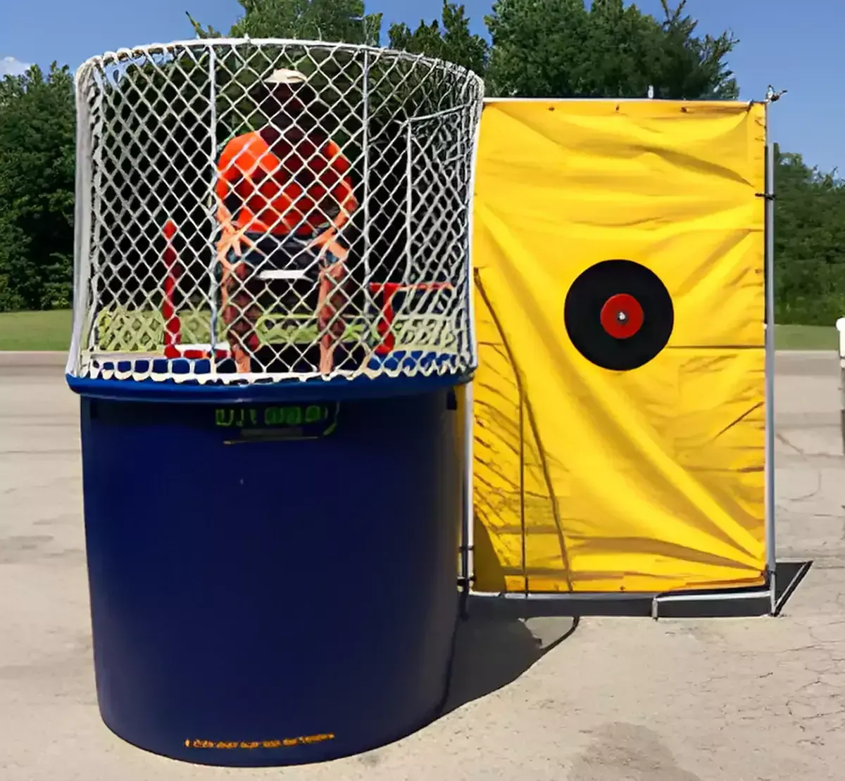 A man sits in a dunk tank next to a yellow target
