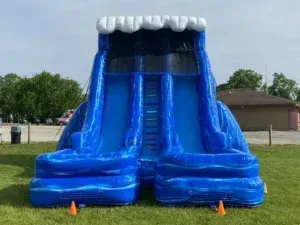 A large inflatable water slide is sitting on top of a lush green field.