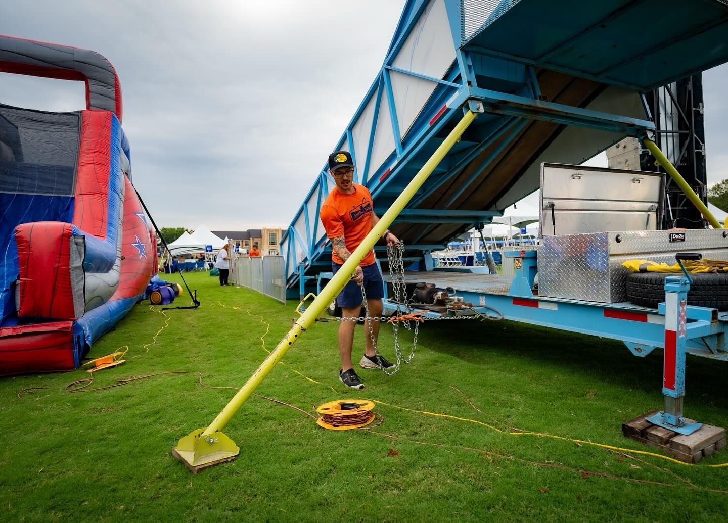 A man is standing in the grass next to a trailer.