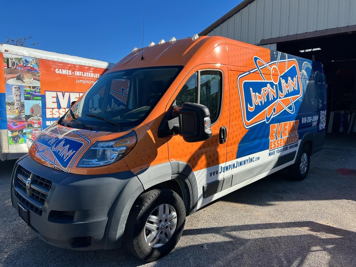 An orange and blue van is parked in front of a building.