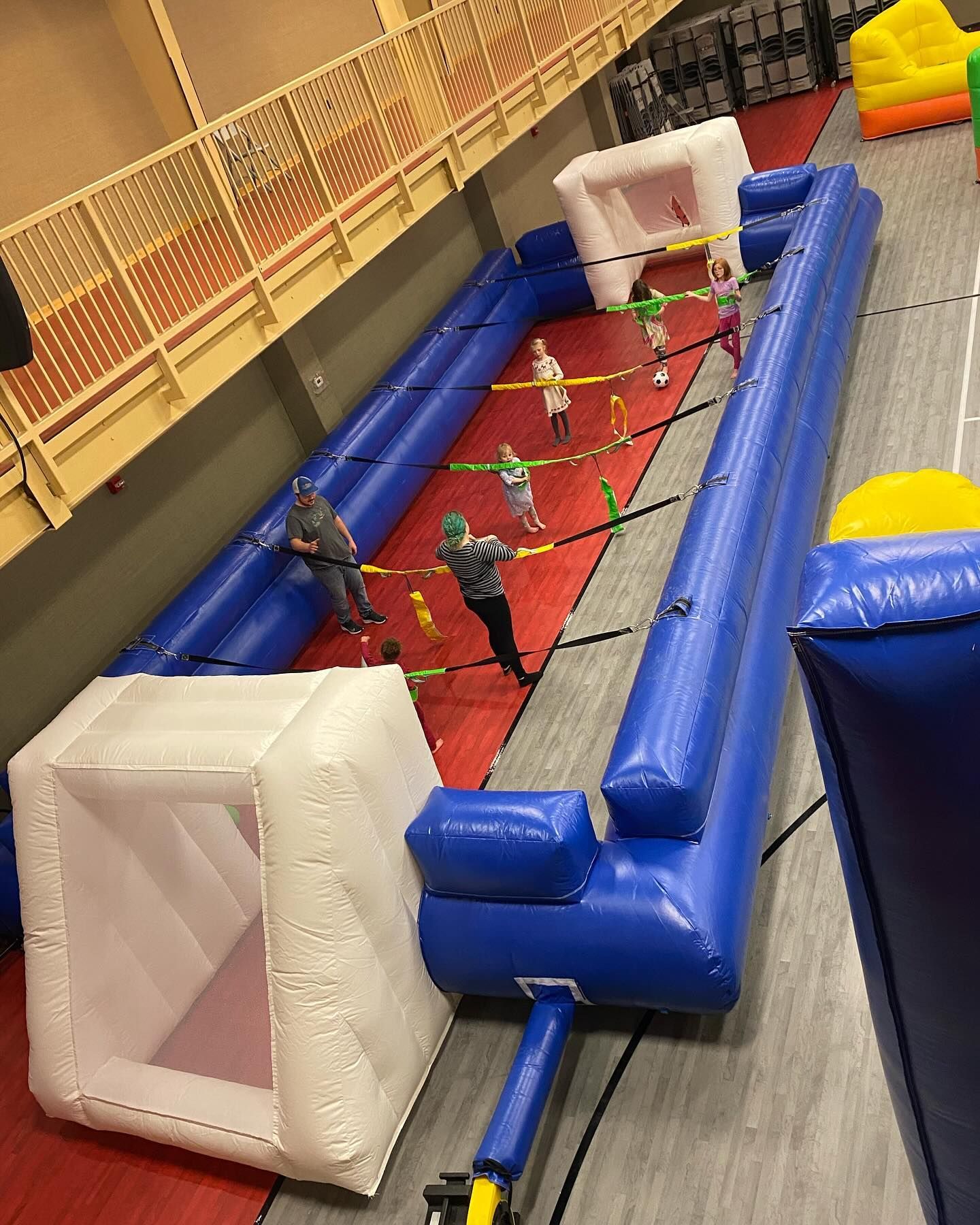 A group of people are playing a game of soccer on a large inflatable field.